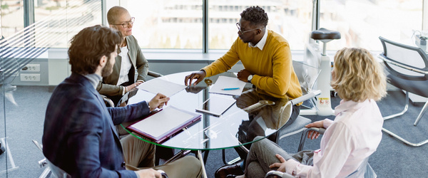 Professionals sitting around a glass table talking