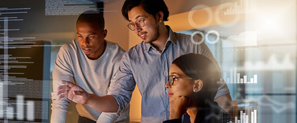 Three people looking at a monitor and working together